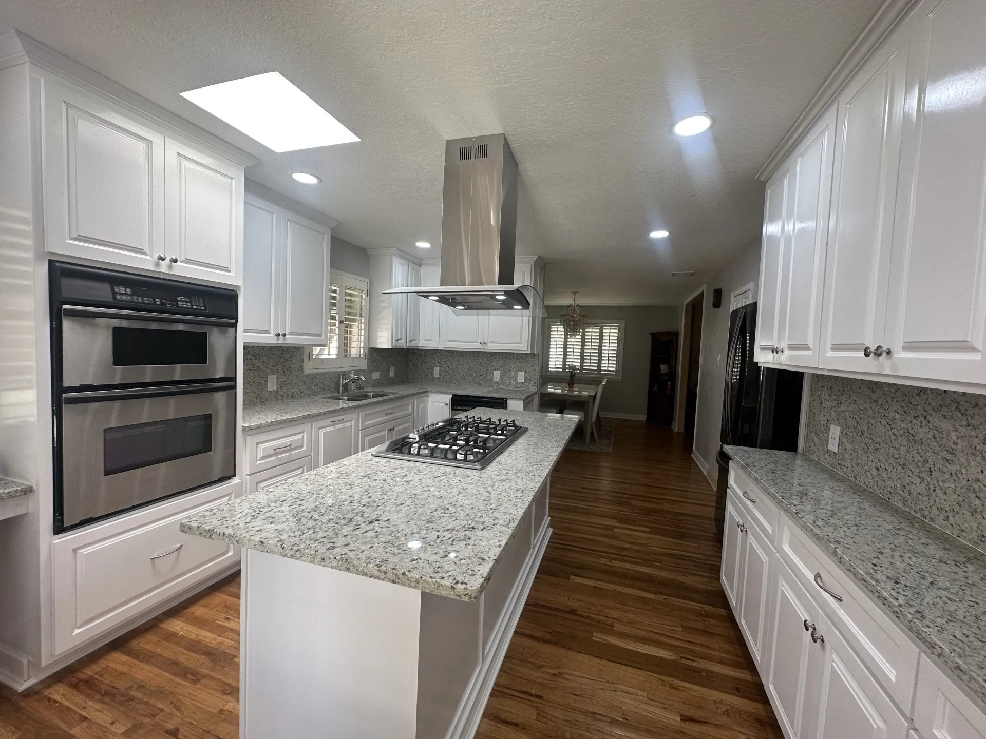 Bright white kitchen with skylight and stainless steel appliances